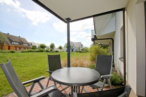 A patio with a round table and four chairs, a covered area, and a view of a residential neighborhood. - Beachfront vacation rental with a terrace, access to the pool and sauna - Rex Rugia - Rex (Göhren)
