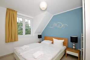 Une chambre à coucher comprenant un lit, deux tables de chevet avec des lampes, une fenêtre avec des rideaux et un motif décoratif sur le mur.