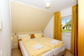 A bedroom with two beds, a window with curtains, a ceiling light, and a view of the outside. - Beachfront vacation rental with a balcony, access to the pool and sauna - Rex Rugia H-1010 - (Göhren)