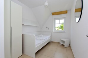 A bedroom with a bed, a window, a small bedside table, and a wardrobe. - Beachfront vacation rental with a balcony, access to the pool and sauna - Rex Rugia H-1010 - (Göhren)