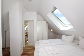 A bedroom with a skylight, a bed, a wardrobe, and a bathroom visible through an open door. - Beachfront vacation rental with a balcony, access to the pool and sauna - Rex Rugia - Rex Rugia (Göhren)