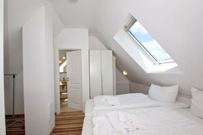 A bedroom with a skylight, a bed, a wardrobe, and a bathroom visible through an open door. - Beachfront vacation rental with a balcony, access to the pool and sauna - Rex Rugia H-1010 - (Göhren)