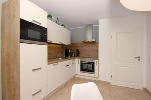 A compact kitchen with white cabinets, a microwave, a stove, and a sink. - Beachfront apartment with a terrace; access to the pool and sauna - Rex Rugia - Rex (Göhren)