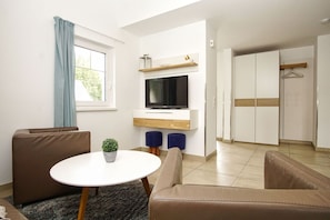 A modern living room with a sofa, a round table, a TV, and a wardrobe.