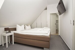 Une chambre moderne avec un lit, une table de chevet et un téléviseur fixé au mur.