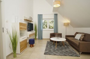 Una sala de estar moderna con un sofá, un televisor, una mesa de centro y una planta.