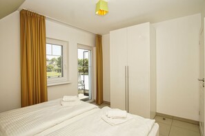 A hotel room with two beds, a wardrobe, a window with curtains, and a view of the outdoors. - Beachfront vacation rental with a balcony, access to the pool and sauna - Rex Rugia - Rex Rugia (Göhren)