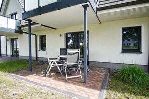 A covered outdoor seating area with a table and chairs, a window, and a door. - Beachfront vacation rental with a terrace, access to the pool and sauna - Rex Rugia - Rex (Göhren)