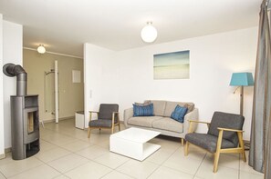 A modern living room with a sofa, two armchairs, a coffee table, a fireplace, and a floor lamp. - Beachfront vacation rental with a terrace, access to the pool and sauna - Rex Rugia - Rex (Göhren)