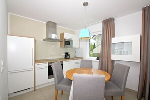 Une cuisine moderne avec un coin repas comprenant une table ronde, des chaises et un luminaire suspendu.