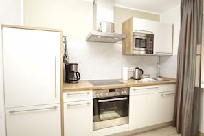 A compact kitchen with a microwave, stove, oven, and coffee maker. - Beachfront vacation rental with a terrace, access to the pool and sauna - Rex Rugia - Rex (Göhren)