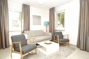 A living room with a sofa, two armchairs, a coffee table, and a lamp.