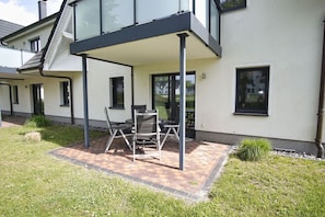 A modern house with a covered patio, a dining table, and chairs. - Beachfront vacation rental with a terrace, access to the pool and sauna - Rex Rugia - Rex (Göhren)