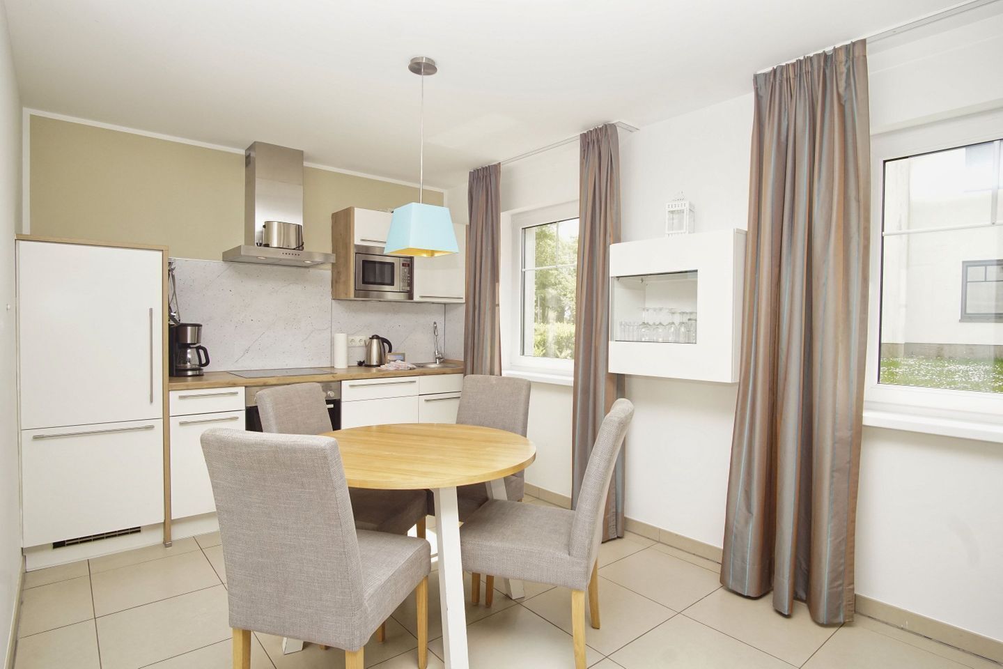 A modern kitchen with white cabinets, a microwave, and a coffee maker. There is a dining table with four chairs.