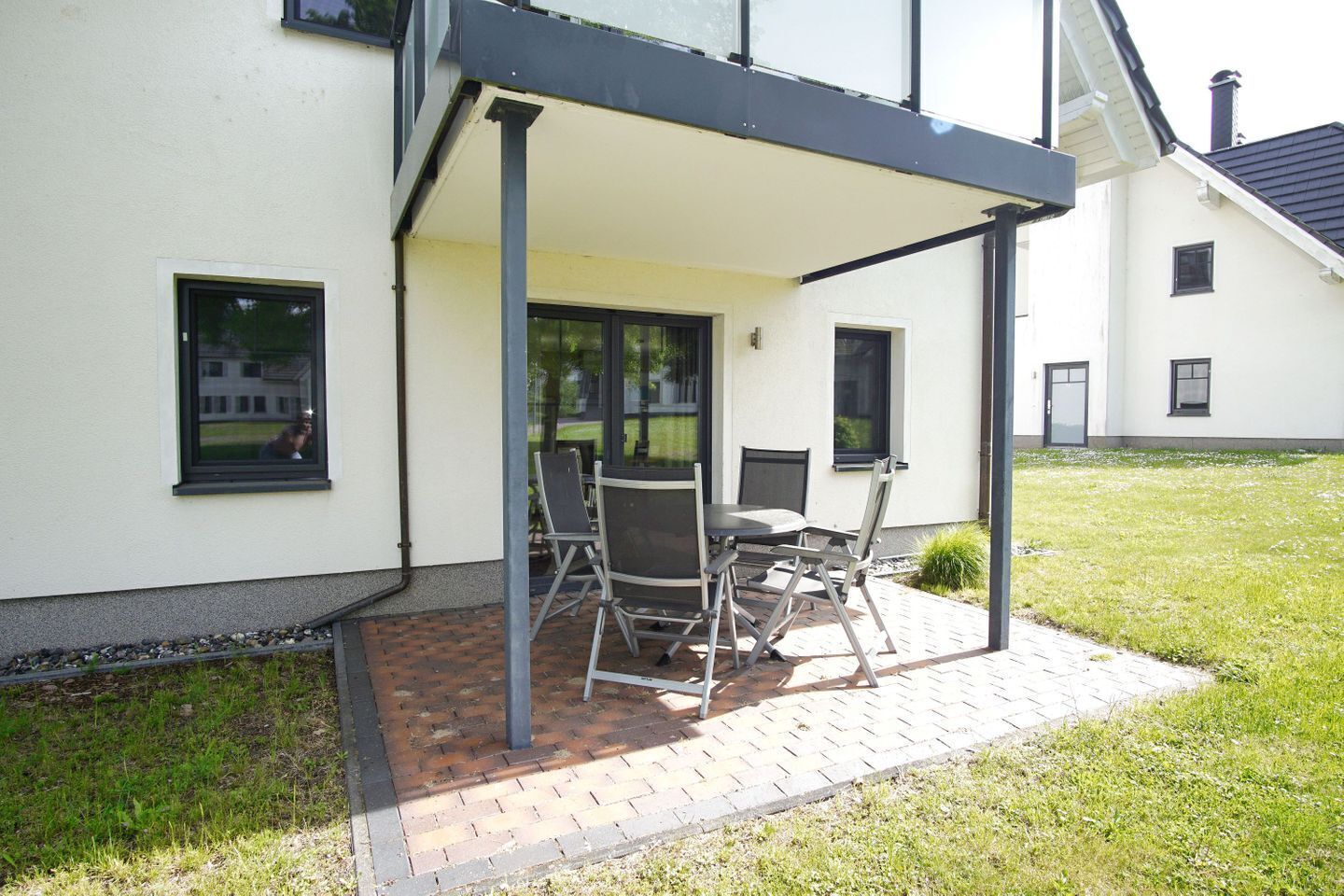 En patio med et bord og stole, et overdækket område og en bygning med vinduer.