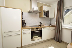 A modern kitchen with white cabinets, a stainless steel oven, a microwave, and a coffee maker. - Beachfront vacation rental with a balcony, access to the pool and sauna - Rex Rugia - Rex Rugia (Göhren)
