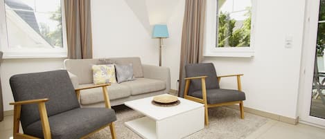A modern living room with a sofa, two armchairs, a coffee table, and a lamp.