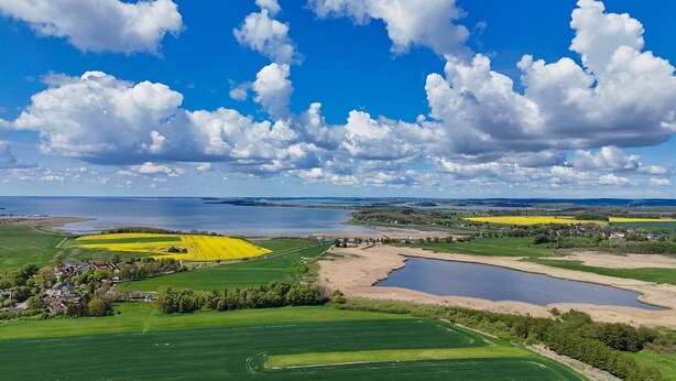 Un paysage rural avec des champs, un lac et un petit village.