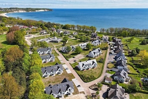 An aerial view of a residential area with houses, roads, and a beach in the background. - Beachfront vacation rental with a balcony, access to the pool and sauna - Rex Rugia H-1010 - (Göhren)