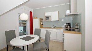 Une cuisine compacte avec un coin repas, un four à micro-ondes, une machine à café et un rideau rouge.