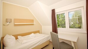 A bedroom with a bed, a desk, and a window. - Beachfront vacation rental with a balcony, access to the pool and sauna - Rex Rugia - Rex Rugia (Göhren)
