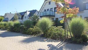 A row of modern houses with a paved driveway and lush greenery. - Beachfront vacation rental with a terrace, access to the pool and sauna - Rex Rugia - Rex (Göhren)