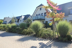 A row of modern houses with a paved driveway and lush greenery.