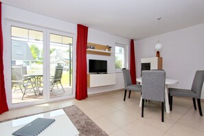 Un salon moderne avec un téléviseur, un canapé et un coin repas.