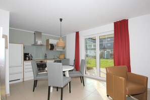A modern kitchen with a dining area, a large sliding glass door to the outside, and a brown leather chair.
