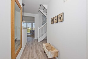 A hallway with a wooden bench, a staircase, and wall-mounted artwork depicting animals.