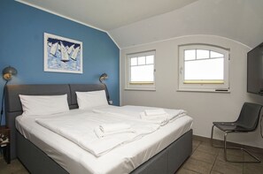 A hotel room with a bed, two windows, a chair, and a painting on the wall. - Near the marina, with a patio, garden, and ocean view—Boddentraum Morgenrot vacation home— (Gager)