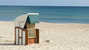 A beach chair with a striped canopy on a sandy beach. - At the sailing harbor, terrace, garden, sea view - vacation home Boddentraum Morgenrot - (Gager)