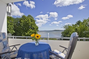 A balcony with a table, chairs, and a vase with sunflowers. - 2-room vacation apartment with a view of the sea from the balcony - Villa Vilmblick FeWo 15 - Villa (Putbus)