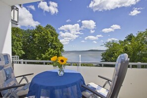 A balcony with a table, chairs, and a vase with sunflowers. - 2-room vacation apartment with sea view from the balcony - Villa Vilmblick FeWo 15 - Villa (Putbus)