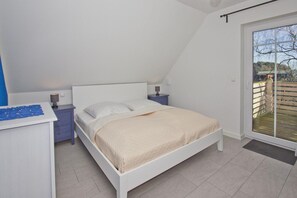 A bedroom with a bed, bedside tables, a desk, and a sliding glass door to an outdoor area.