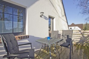 An outdoor patio with a table and chairs, a window, and a light fixture.