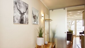A modern interior with a wooden bench, a potted plant, and two wall-mounted artworks depicting antlers.