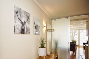 Ein modernes Interieur mit einer hölzernen Bank, einem Blumentopf und zwei Wandbildern mit Geweihmotiven.