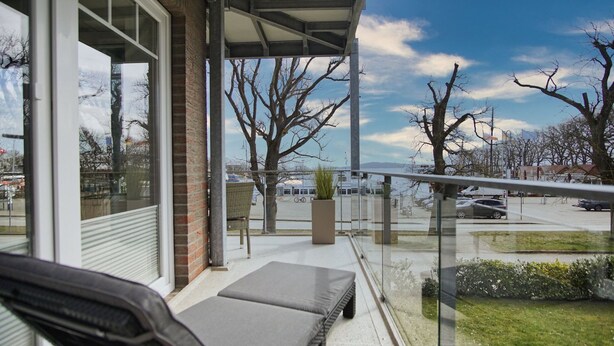 A balcony with a view of a parking lot and trees.