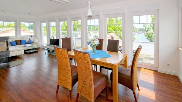 A spacious living room with a dining area, large windows, and a view of the outdoors.