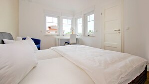 A bedroom with two beds, a desk, and a chair.