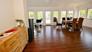 A spacious room with a wooden dresser, a dining table with chairs, and a TV.