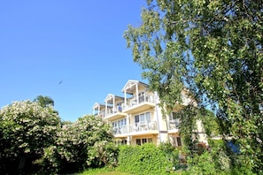 A multi-story building with balconies, surrounded by lush greenery and trees. - Right behind the dune, with a balcony and a view of the sea - Strandvilla Böck FeWo 10 - (Glowe)