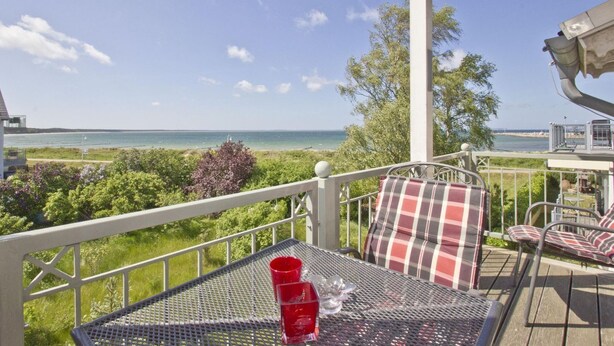 A balcony with a table and chairs, overlooking a beach and ocean. - Directly behind the dune, with balcony and sea view - Strandvilla Böck FeWo 15 - (Glowe)