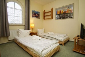 A hotel room with two single beds, a desk with a computer, a lamp, and two paintings on the wall. - Right behind the dune, with a balcony and a view of the sea - Strandvilla Böck FeWo 15 - (Glowe)