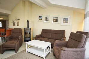 A living room with a sofa set, a white coffee table, a fireplace, and framed pictures on the wall. - Right behind the dune, with a balcony and a view of the sea - Strandvilla Böck FeWo 15 - (Glowe)