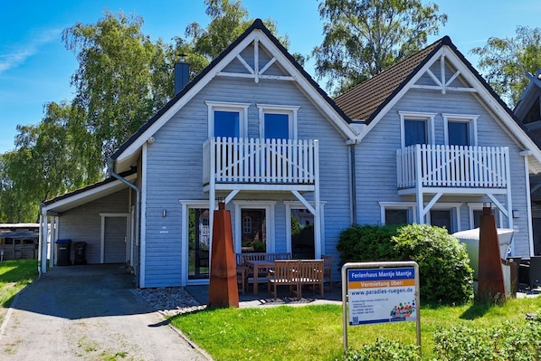 A two-story house with a balcony, a front porch, and a sign indicating it's a rental property.