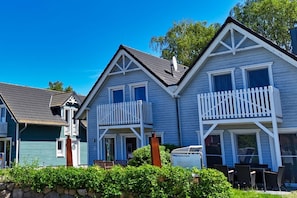 A row of two-story houses with balconies, a stone wall in front, and a sign for 'Ferienhaus.'