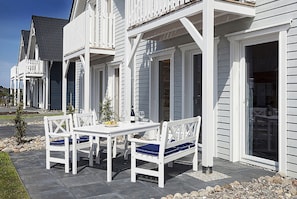 A white building with a covered patio area featuring a table and chairs.