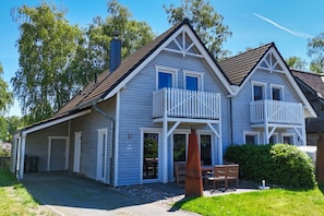 A two-story house with a balcony, a chimney, and a front porch with a bench.